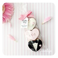 three cookies in the shape of grooms and bride's suits with pink flowers