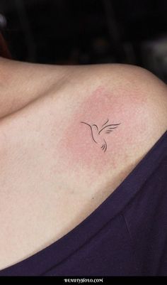 a woman with a small tattoo on her shoulder that has a bird flying above it