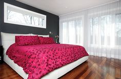 a bed with red and black comforter in a bedroom next to a large window