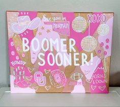 a sign that says boomer soon on it with pink and gold decorations in the background