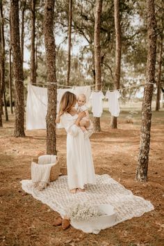 a woman holding a baby in the woods