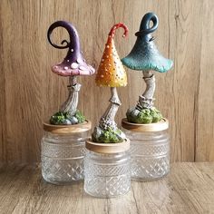 three small glass vases sitting on top of a wooden table next to each other