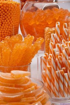 candy and candies are arranged in glass containers on a table with orange striped straws