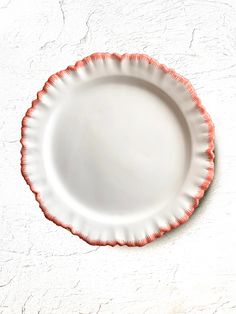 a white plate with an orange edge on a table