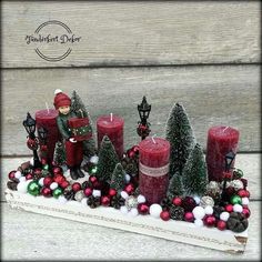 some red candles are sitting next to christmas decorations