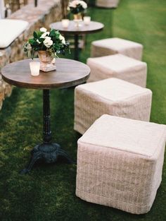 tables and stools are lined up on the grass with flowers in vases sitting on them