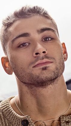 a close up of a person with a necklace on his neck and an earring