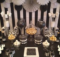 a table topped with lots of desserts next to black and white wall paper decorations