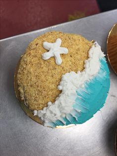 a cupcake with white frosting and a starfish decoration on top is sitting on a metal tray