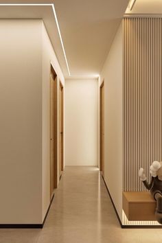 an empty hallway with white walls and beige flooring, along with two black chairs