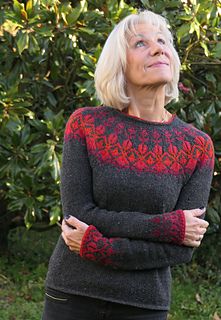 an older woman standing in front of some bushes and trees with her arms crossed looking up