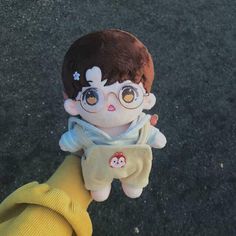 a small doll with big eyes holding onto someone's hand while they both wear glasses