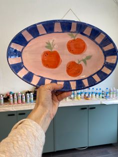 a person holding up a plate with oranges on it in front of a counter