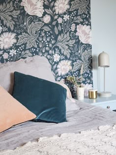 a bed with two pillows on top of it next to a night stand and lamp