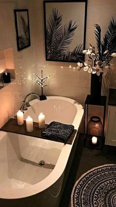 a white bath tub sitting in a bathroom next to a rug and candles on the floor