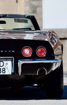 the back end of an old black car with its license plate on it's bumper