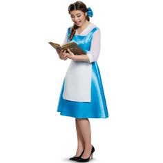 a woman in a blue and white dress is holding a book while looking at it