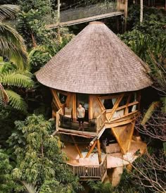 a tree house in the middle of trees with people standing on it's roof