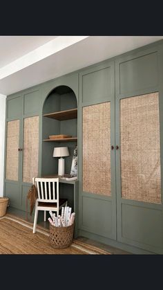 an empty room with green painted cabinets and wicker shades on the doors, along with a white chair