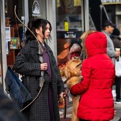 a woman in a red coat is talking to a man with a bow and arrow