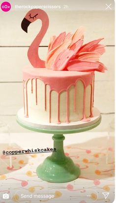 a cake with pink icing and a flamingo on top that is sitting on a table