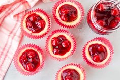 small cupcakes with jam in the middle on a white surface next to a jar of jam