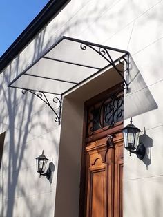 the front door of a building with two lights on each side and a large wooden door