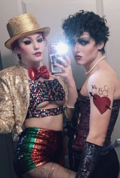 two women dressed up in costumes taking a selfie with a cell phone while wearing hats and sequins