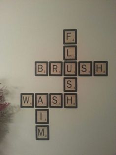 a cross made out of scrabble tiles sitting on top of a white wall