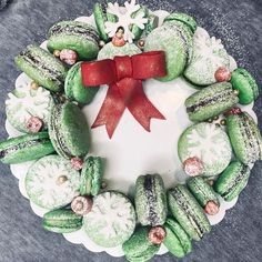 a white plate topped with green macaroons covered in frosting and a red bow