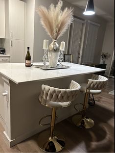 two bar stools sit in front of an island with wine bottles and candles on it