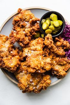 fried food on a plate with coleslaw, pickles and sprouts