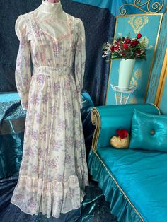 "Gunne Sax dress, high neck Victorian style in cream cotton voile with pink, violet, and teal flowers.the neckline is shear with lace touches; framed by pink and cream satin ribbon. The long sleeves have a 3\" cuff and the ruffle on the, full, skirt is topped with lace trim. SiE 13, bust 38/38\", waist 30\", waist to hem 43\"s, washable" Feminine Victorian Dress For Daywear, Vintage Long Sleeve Prairie Dress For Garden Party, Feminine Vintage White Dress, Cream Long Sleeve Dress For Vintage Events, Long Sleeve Cream Dresses For Vintage Events, Long Sleeve Prairie Dress For Wedding, Cream Victorian Dress With Long Sleeves For Spring, Purple Vintage Victorian Dress For Wedding, Cream Long Sleeve Vintage Style Dresses