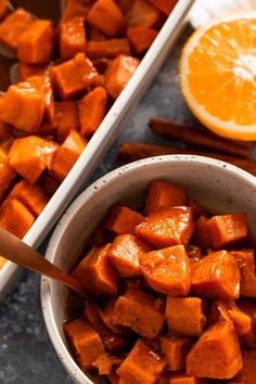 a bowl filled with sweet potatoes next to an orange and cinnamon stick on the side