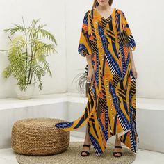 Bask in the glow of the Savannah Sunrise with our African Print Kaftan Robe, a celebration of tribal aesthetics and modern design. This imitation silk V-neck robe is a masterpiece of vibrant colors and bold patterns that reflect the spirit and artistry of the African continent. Each robe is a canvas of orange, blue, and white motifs, reminiscent of the dynamic energy of a sunrise across the savannah. The lightweight blend of 97% polyester and 3% spandex offers a luxurious feel and flowy grace, p Yellow Printed V-neck Kaftan, V-neck Kaftan With Vibrant Print For Beach, Vibrant Print V-neck Kaftan For Beach Cover-up, Casual Yellow V-neck Kaftan, Printed V-neck Free Size Kaftan, Free Size V-neck Kaftan For Festival, Modern African Fashion, Robe Kente, African Continent