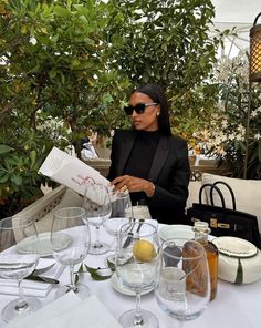 a woman sitting at a table with wine glasses and an open menu in front of her