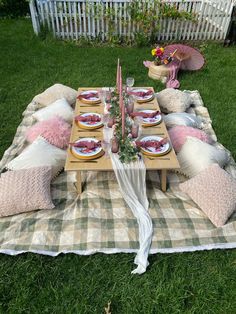 a picnic table set up with pink and white pillows