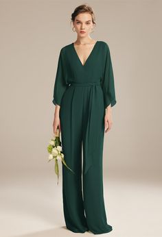 a woman in a green jumpsuit holding a flower