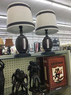 two lamps with footballs on them are sitting on a shelf in a store next to books