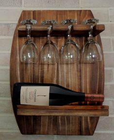 a wooden wine rack with six wine glasses and a bottle in it on a brick wall