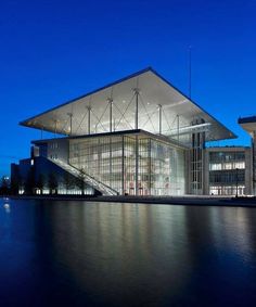 the building is lit up at night and reflecting in the water