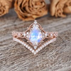 a white diamond ring sitting on top of a wooden table next to some rose petals