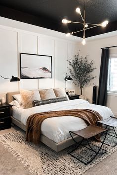 a bedroom with white walls, black ceiling and carpeted flooring that has a large bed in it