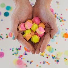 two hands holding colorful marshmallows in front of confetti sprinkles