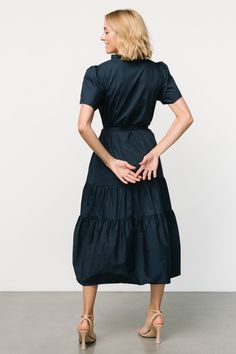 A simple and easy-to-wear dress with cute details Deep navy blue color Cotton material has no stretch Fit runs big, we recommend sizing down if wanting a more fitted look V-neckline with ruffled collar Three functional loop buttons on front bodice Removable self-tie waist sash Functional side pockets Tiered skirt Unlined 100% Cotton Trina is 5'6, cup size 32D, size 2 and is wearing size XS Navy Cotton Midi Dress For Spring, Fitted Cotton Tiered Midi Dress, Fitted Tiered Cotton Midi Dress, Navy Cotton Midi Dress, Cotton Tiered V-neck Dress With Ruffle Hem, Fitted Cotton Midi Dress With Tiered Skirt, Fitted Tiered Dress With Ruffle Hem And V-neck, Navy Ruffled Midi Dress, Navy Ruffled Midi Dress For Summer