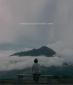 a man sitting on top of a bench looking at the clouds in the sky and mountains