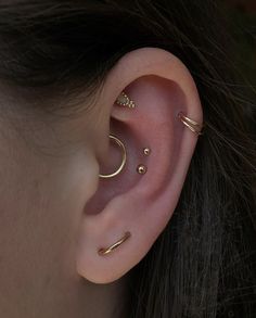 a woman wearing three different types of ear piercings