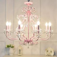 a pink chandelier hanging from the ceiling in a room with white walls and furniture