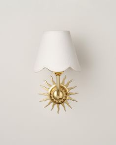 a wall light with a white shade on it's side and a gold finish