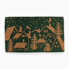 a green door mat with houses and trees on it in the snow, against a white background